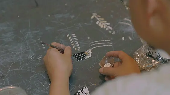 Placing a shard of eggshell into the wet lacquer