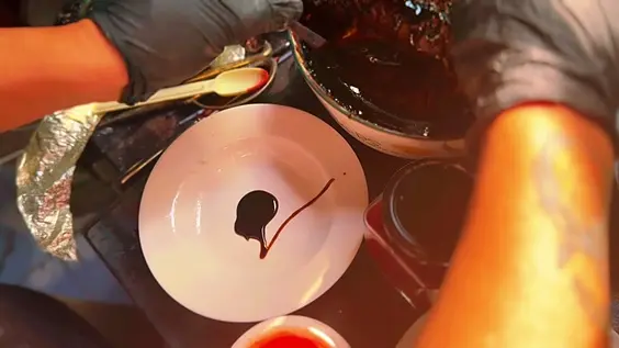 Pigment being mixed in a shallow bowl beside gold leaf