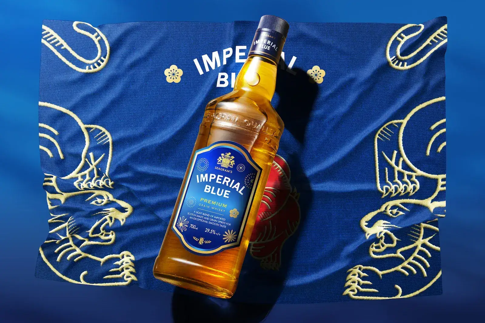 The Imperial Blue bottle lying on embroidered silk, gold tigers stitched across the cloth