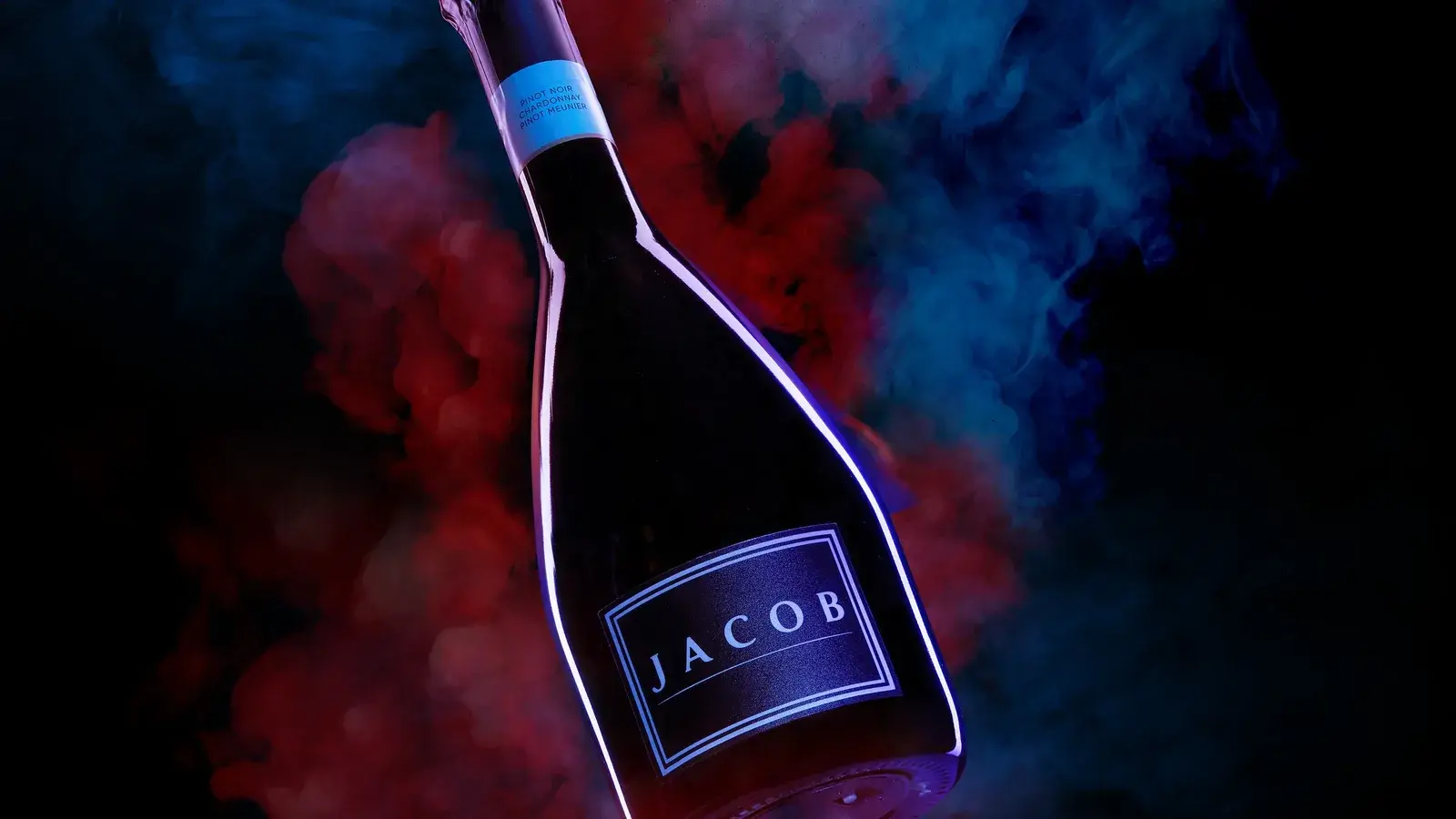 Wide frame — red and blue smoke pushed against each other around the bottle